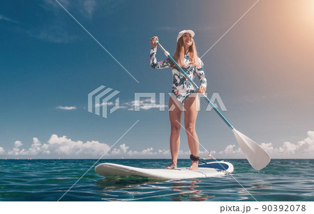 Healthy happy fit woman in bikini relaxing on a sup surfboard, floating on the clear turquoise sea water. Recreational Sports. Stand Up Paddle boarding. Summer fun, holidays travel. Active lifestyle 90392078