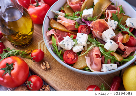 Salad with jamon or prosciutto, pears, tomatoes and arugula on wooden board 90394093