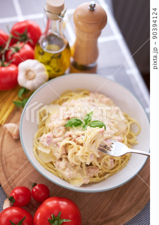 homemade pasta carbonara with fresh basil and parmesan in ceramic dish 90394124
