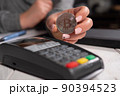 Close-up of a young woman holding a silver bitcoin coin near the terminal. BTC. 90394523