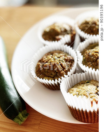 白い皿にのっている手作りズッキーニマフィンとズッキーニ 白い皿にのっている手作りズッキーニマフィンとズッキーニ 90395196