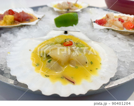 White fish in sauce seasoned with red pepper lies in a shell on ice close-up. High quality photo 90401204