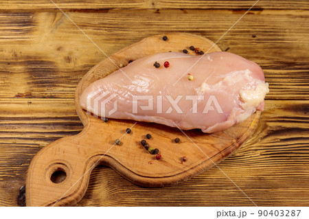 Raw chicken breast on cutting board on wooden table 90403287