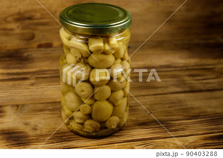 Delicious marinated mushrooms in glass jar on wooden table 90403288