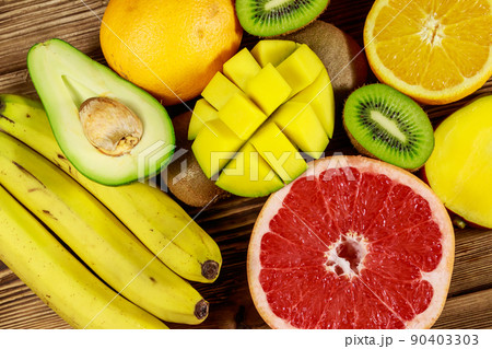 Assortment of tropical fruits on wooden table. Still life with bananas, mango, oranges, avocado, grapefruit and kiwi fruits Assortment of tropical fruits on wooden table. Still life with bananas, mango, oranges, avocado, grapefruit and kiwi fruits 90403303