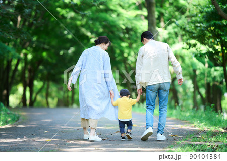 手を繋いで公園を歩く家族 90404384