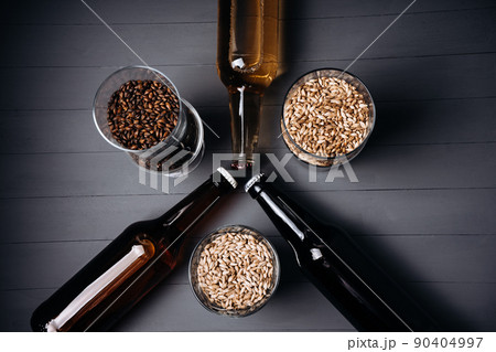 bottles with craft beer  and beer glasses with barley malt on a grey wooden background.  Ale or lager from pilsner malt.  homemade home-brewed beer. 90404997