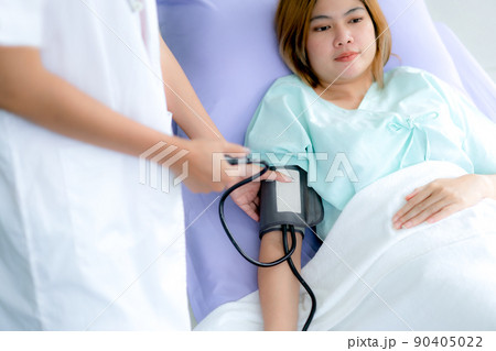 Patient is having blood pressure measured at the hospital for a check-up by a nurse. 90405022