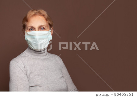 Nurse or medical worker mature woman wearing medical mask on brown wall banner background  90405551