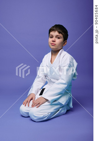 European teenage boy - aikido fighter in a white kimono during the practice of oriental martial arts. European teenage boy - aikido fighter in a white kimono during the practice of oriental martial arts. 90405684