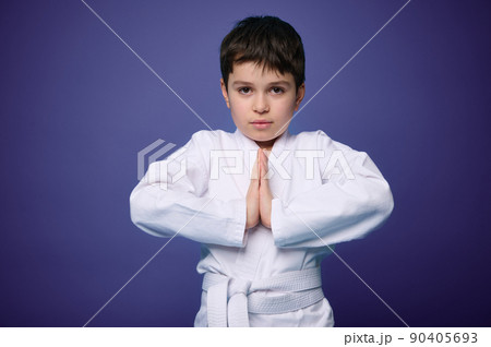 Waist length portrait of a strong European teenage boy, aikido fighter practicing martial skills against violet wall background, copy ad space Waist length portrait of a strong European teenage boy, aikido fighter practicing martial skills against violet wall background, copy ad space 90405693