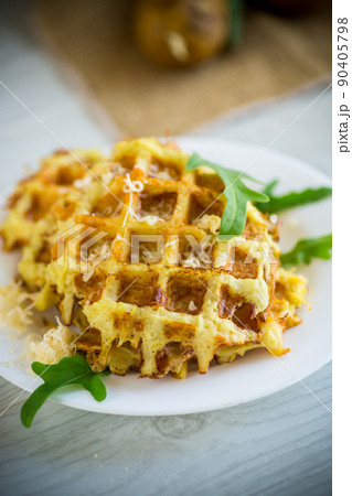 fried potato waffles with cheese in a plate on wooden table. 90405798