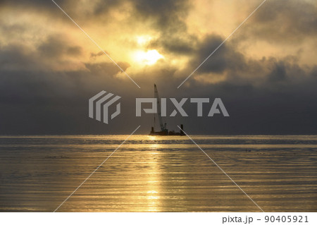 Beautiful sunset in Arctic sea. Barge with crane. Golden hour. Construction Marine offshore works. Dam building, crane, barge, dredger. 90405921