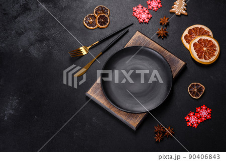 Christmas table setting with empty black ceramic plate, fir tree and black accessories Christmas table setting with empty black ceramic plate, fir tree and black accessories 90406843