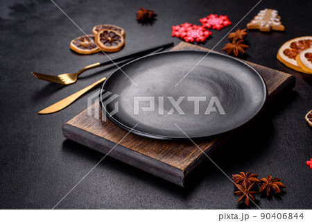 Christmas table setting with empty black ceramic plate, fir tree and black accessories Christmas table setting with empty black ceramic plate, fir tree and black accessories 90406844