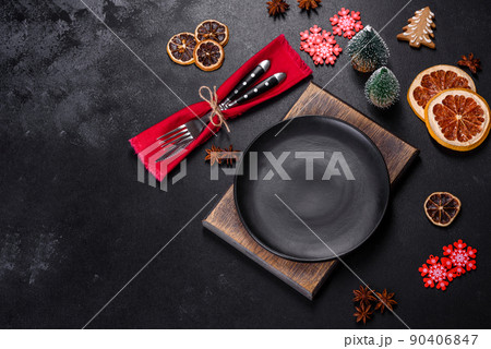 Christmas table setting with empty black ceramic plate, fir tree and black accessories 90406847