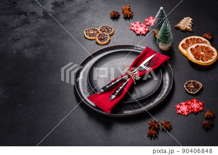 Christmas table setting with empty black ceramic plate, fir tree and black accessories 90406848