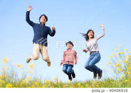 屋外で一緒にジャンプする3人家族 90406916