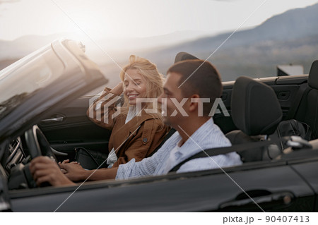 Close up of happy couple man and woman traveling driving a convertible car, side view 90407413