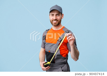 Smiling repairman worker in uniform holding measure tape and looking camera  90407414