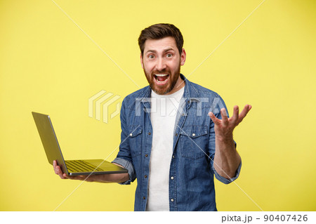 Emotional man holding a laptop and shouting actively gesturing with his hands Emotional man holding a laptop and shouting actively gesturing with his hands 90407426