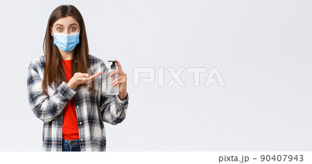 Coronavirus outbreak, leisure on quarantine, social distancing and emotions concept. Smiling girl preventing catching virus, wear medical mask and apply hand sanitizer, white background 90407943