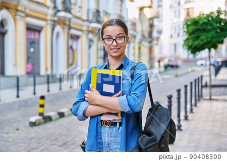 Outdoor portrait of smiling teenage female student looking at camera in city Outdoor portrait of smiling teenage female student looking at camera in city 90408300