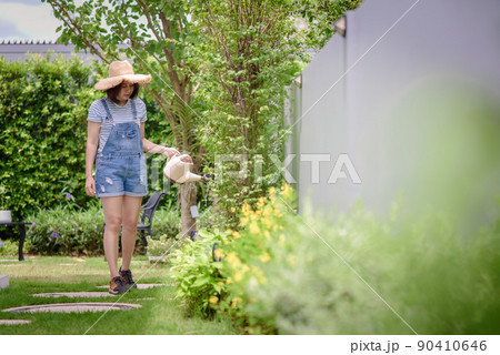 An Asian woman is watering plants in the garden. An Asian woman is watering plants in the garden. 90410646
