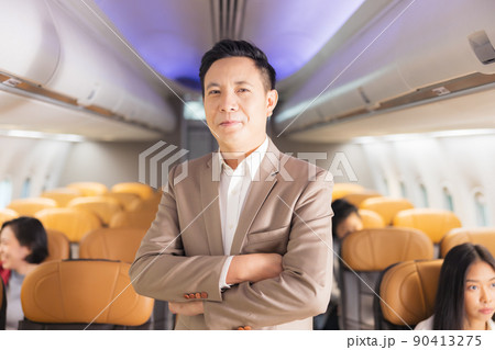 In the plane, there is a young passenger. portrait of a man standing in an airplane aisle 90413275