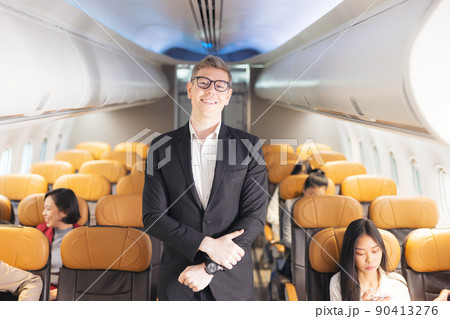 In the plane, there is a young passenger. portrait of a man standing in an airplane aisle In the plane, there is a young passenger. portrait of a man standing in an airplane aisle 90413276