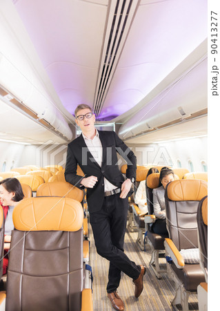 In the plane, there is a young passenger. portrait of a man standing in an airplane aisle In the plane, there is a young passenger. portrait of a man standing in an airplane aisle 90413277