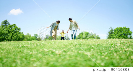 緑の丘で遊びまわる家族 90416303