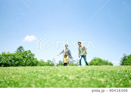 緑の丘で遊びまわる家族 90416306
