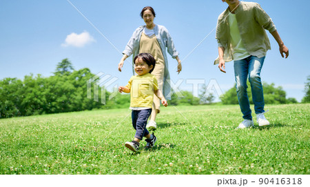 緑の丘で遊びまわる家族 90416318