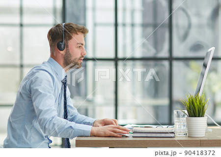 Man with headphones and laptop working in office Man with headphones and laptop working in office 90418372