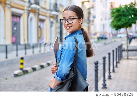 Outdoor portrait of smiling teenage female student looking at camera in city 90420829