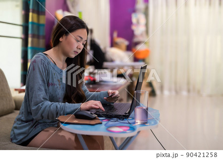 Asian lady on sofa, use laptop and hold credit card to shopping online 90421258
