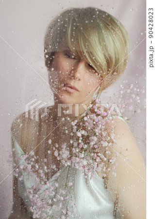 Portrait of a girl on a pink background with flowers. Tenderness and feminine. The sphere of beauty and women's health. Short haircut, blonde hair 90428023