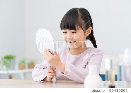 鏡で抜けた歯を見る小学生の女の子 90430002