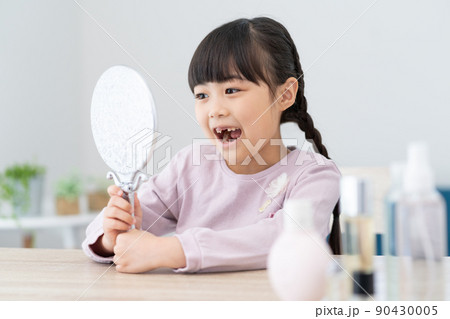 鏡で抜けた歯を見る小学生の女の子 90430005
