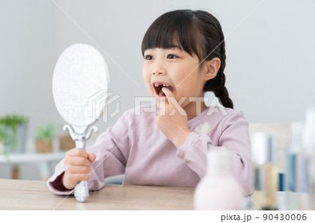 鏡で抜けた歯を見る小学生の女の子 90430006