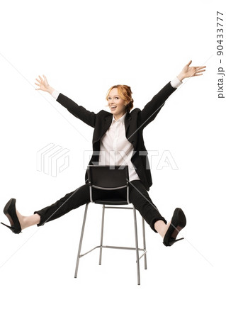 Delighted young businesswoman sitting on chair with hands and legs apart 90433777