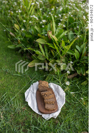 Composition of homemade custard bread on wood board with white cloth napkin on the green grass. High quality photo 90434672