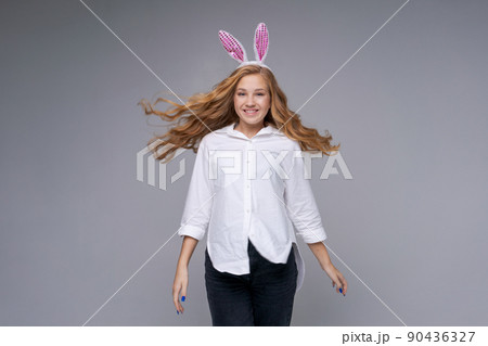 Girl in rabbit ears on her head against backdrop studio. Cheerful suffering 90436327