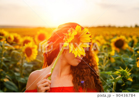 Cute young woman is holding sunflower in her hand while 90436784