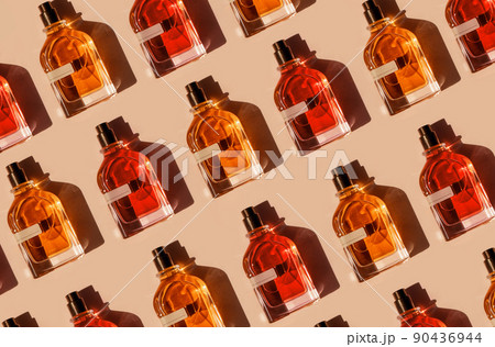 Pattern of different perfume bottles on a pastel beige background in the sunlight. Flat lay, top view. Luxury presentation mockup. Red, yellow and orange samples of aroma water 90436944