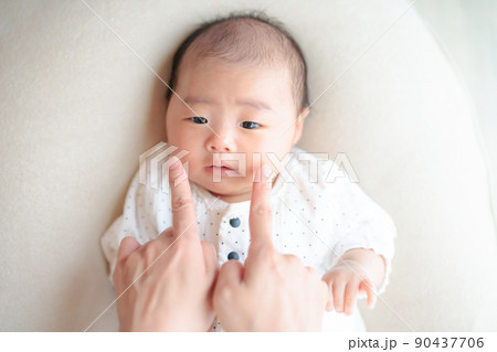 親子のふれあい　不安げな表情の赤ちゃんのほっぺをつつく  困り顔　コミュニケーション 90437706