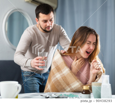 Man giving glass of water to his ill wife at home Man giving glass of water to his ill wife at home 90438293