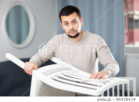 Young man wiping chair with duster at home Young man wiping chair with duster at home 90438419