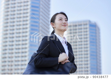 リクルートスーツの若い女性　青空　高層ビル　笑顔 90438477